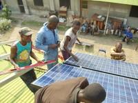 Photo shows Villagers install a solar panel array on a roof-top