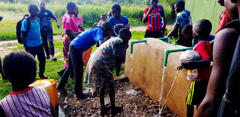 Children access the village water source in Kitenda, DRC.