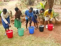 Photo shows Students stir water purification packets into the bucket